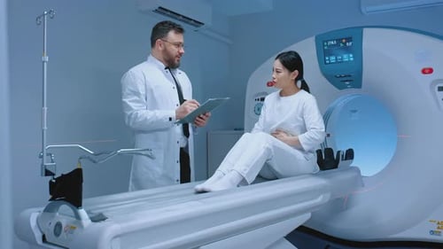 Doctor Consults Patient Near CT Scan Machine in Hospital