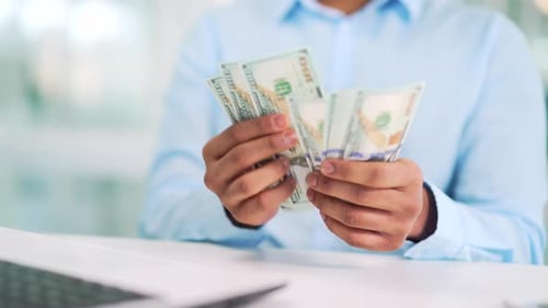 Close up of male hands counting US hundred dollar bills. A businessman in a shirt counts banknotes a