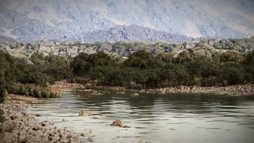 Ruhiger Fluss fließt durch felsiges Gelände unter klarem Himmel