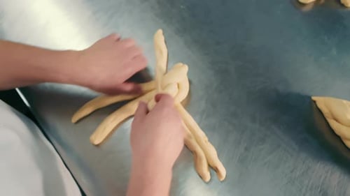 Baker Braiding Dough on Metal Surface