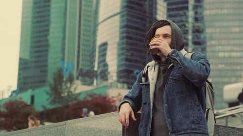 Man with Dreadlocks Drinks Coffee in City