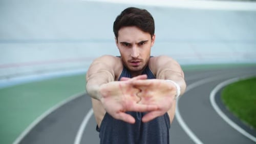 Sportsman Exercising At Sport Stadium. Closeup View Of Man Runner Stretching Arms On Athletics Tr...