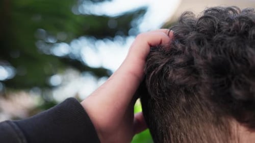 Young Adult with Curly Hair Scratching Head