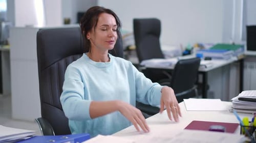 A Focused Professional Working Purposefully at Their Desk Surrounded By Documents