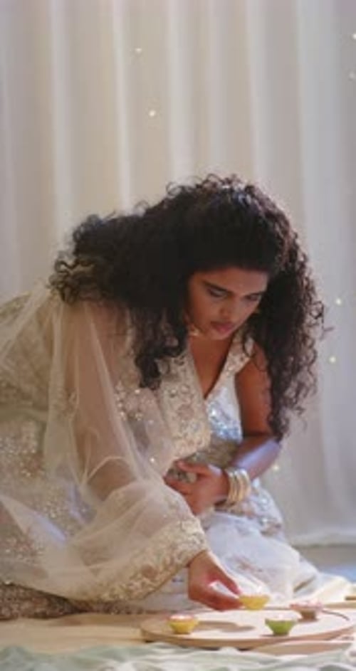 Vidéo verticale : Bol à cocher, femme indienne vêtue d'une robe ornée, arrangeant des bols sur un plateau de sol pour un rituel