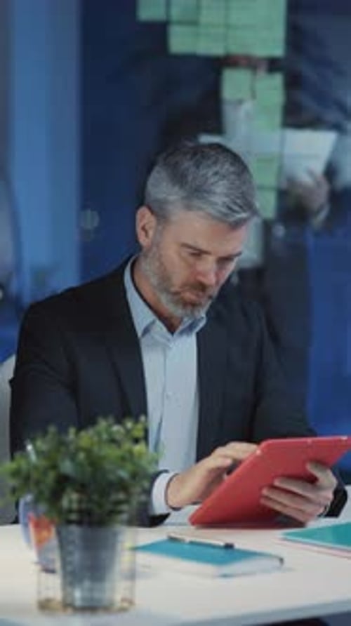 A Focused Businessman Engaged with His Tablet in a Modern and Dynamic Office Environment