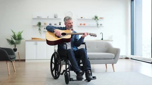 Man in Wheelchair Plays Guitar in Modern Apartment