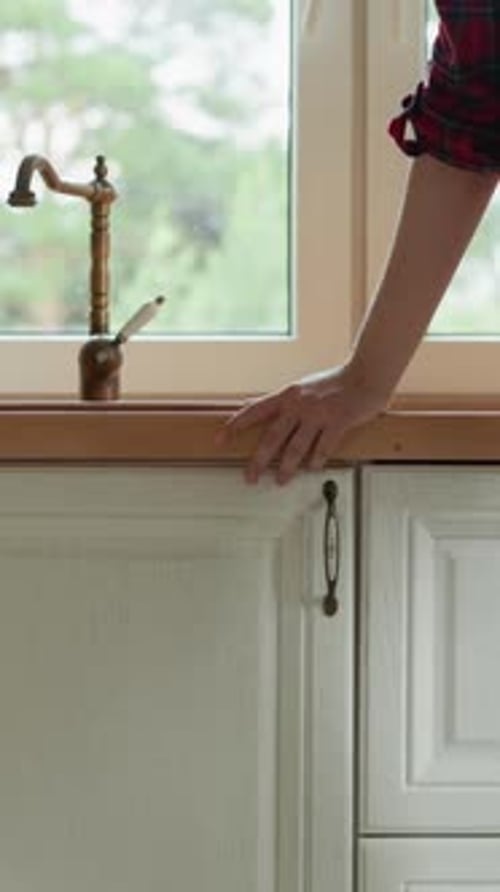 Woman Leans on Countertop By Kitchen Sink