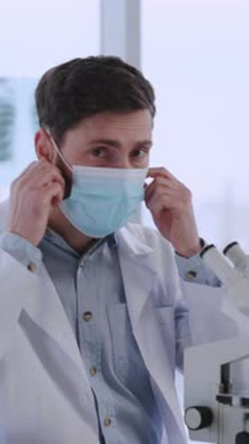 Attractive Young Doctor Scientist in Microbiology Center Smiling to Camera Using Microscope