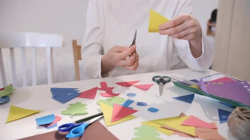 Woman Making Colorful Christmas Decorations with Scissors