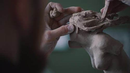 Focus on the Hands of a Sculptor Carving Hair on a Clay Statue of Woman Bust in the Potting Workshop
