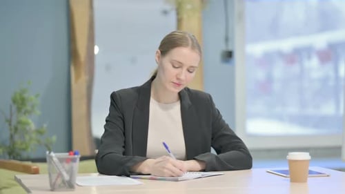 Businesswoman Writing while Sitting in Office