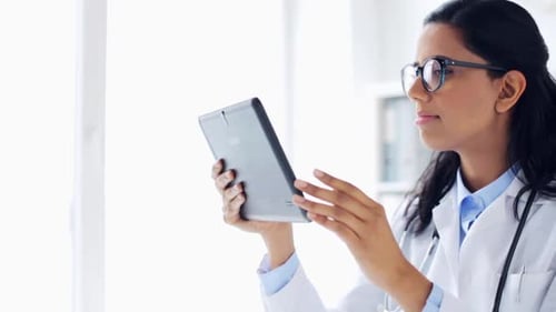 Female Doctor Examining Digital Tablet in Bright Office