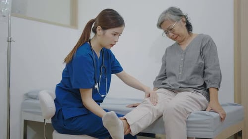 Healthcare Worker Examining Senior Woman's Knee in Hospital