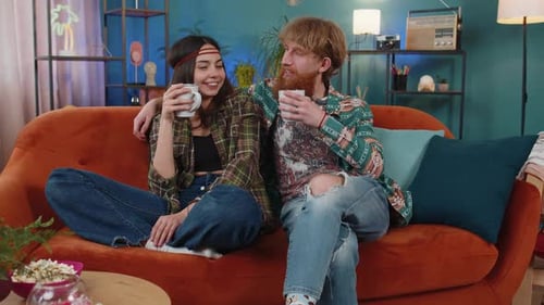Casually Dressed Couple Relaxing on Orange Sofa