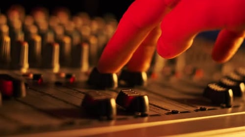Sound Engineer Moves Faders Up and Down on Audio Mixer in Neon Light CloseUp