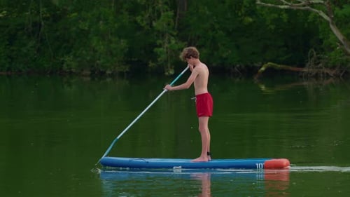 Alone Boy Floating on Stand Up Paddle Board in Lake in Summertime Standup Paddleboarding Surfer Rows