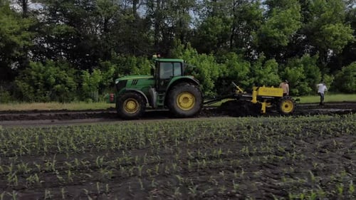Grader works with tractor and levelling the field road