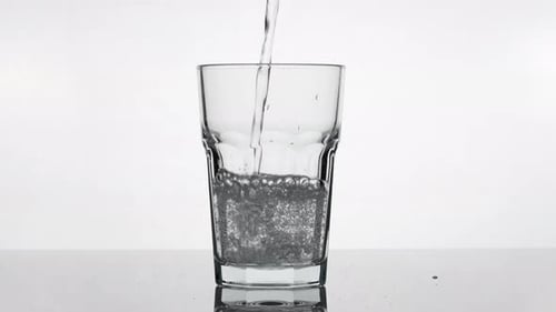 De l'eau minérale gazeuse se déversant dans un verre au ralenti