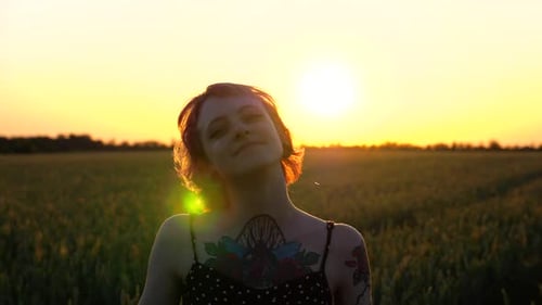 Happy Female Hipster with Tattoos Having Fun During Goes Through Green Barley Field at Beautiful