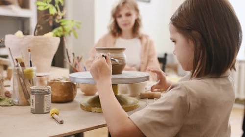 Child Shaping Clay on Potter's Wheel with Adult