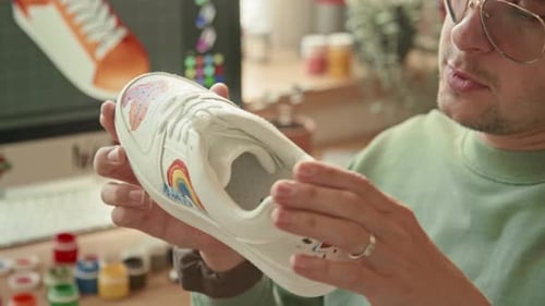 Young Adult Customizing White Tennis Shoe at Home