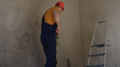 Worker Priming Interior Walls Using a Paint Roller in a Residential Space During Renovation Project
