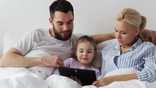 Happy Family Using Tablet Together in Bed