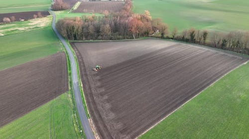 Aerial View of Tractor Plowing Agricultural Farm Field Preparing Soil for Seeding in Summer