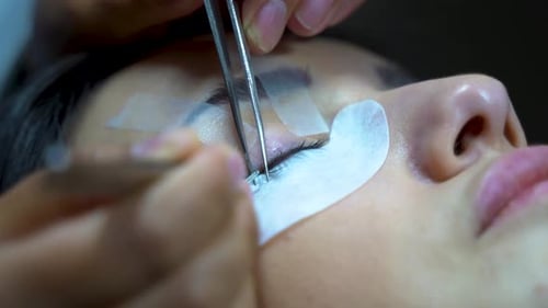 Woman with long eyelashes in a beauty salon. Eyelash extension procedure. Lashes close up 4K