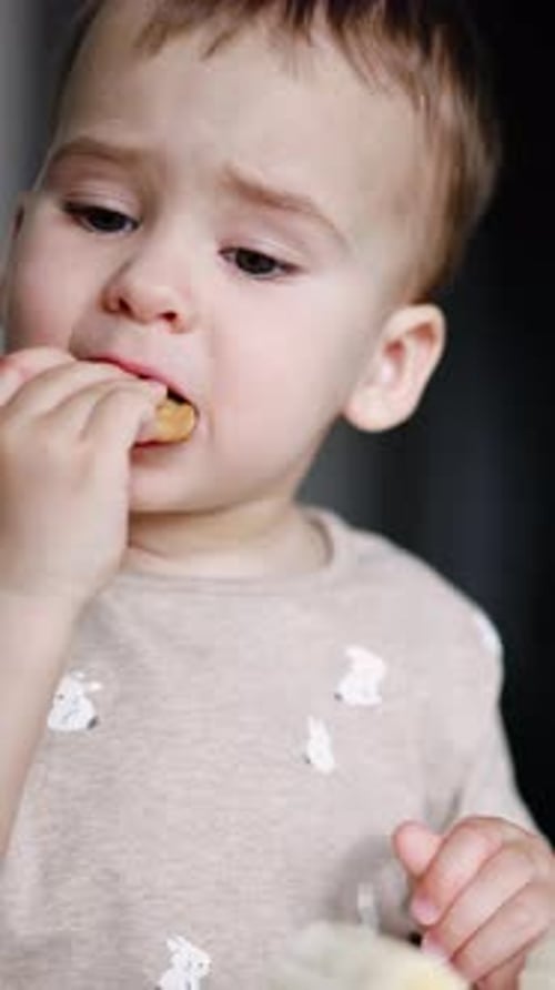 Toddler Eating Cracker and Looking Thoughtful Indoors