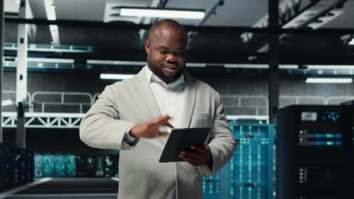 Smiling Admin Using Tablet in in Data Center Maintaining Infrastructure