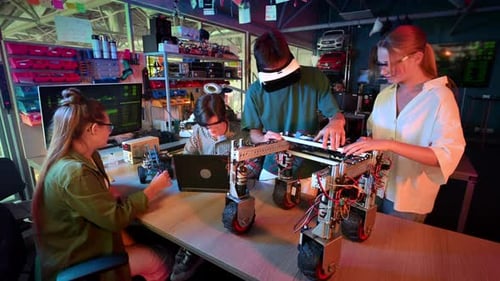 Group of teens doing experiments in robotics in a laboratory. Boys and girls in protective and VR gl