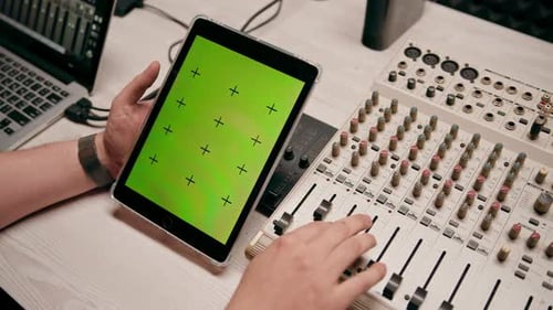 ingeniero de sonido de estudio de grabación profesional que sostiene una tableta con pantalla verde cerca del ecualizador, mezclador