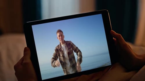 Liegende Frau schaut sich Tablet-Video in Nahaufnahme des Abendschlafzimmers an