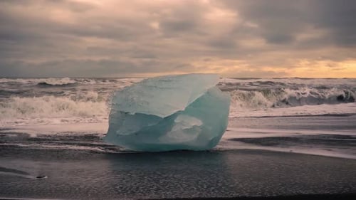 Slow motion shots of blue icebergs on Diamond beach in Iceland. Black sand beach at sunset. Differen