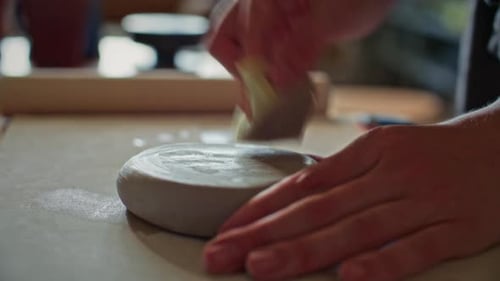 Hands of Female Potter Wiping Clay with Wet Sponge on Table in Ceramic Studio