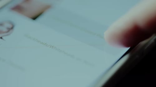 Finger scrolls through list on smartphone screen close-up