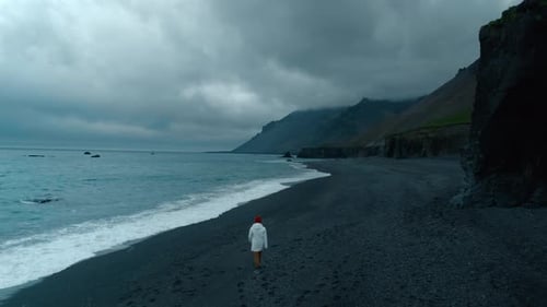 Man Walk on Empty Moody Black Sand Beach