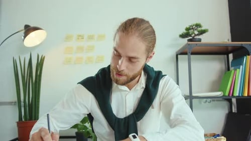 Bearded Man Talking and Working at Desk