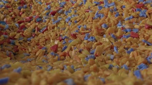 Colorful shredded plastic flakes yellow blue red at recycling factory