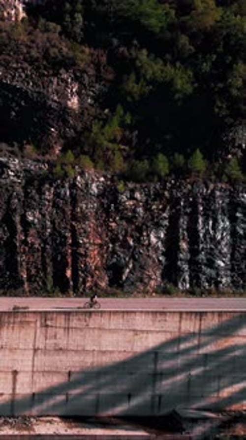 Cyclist on road bicycle climbing up on asphalt road in mountains. Vertical video