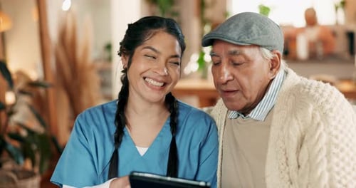 Caregiver and Senior Man Using Tablet Together Indoors