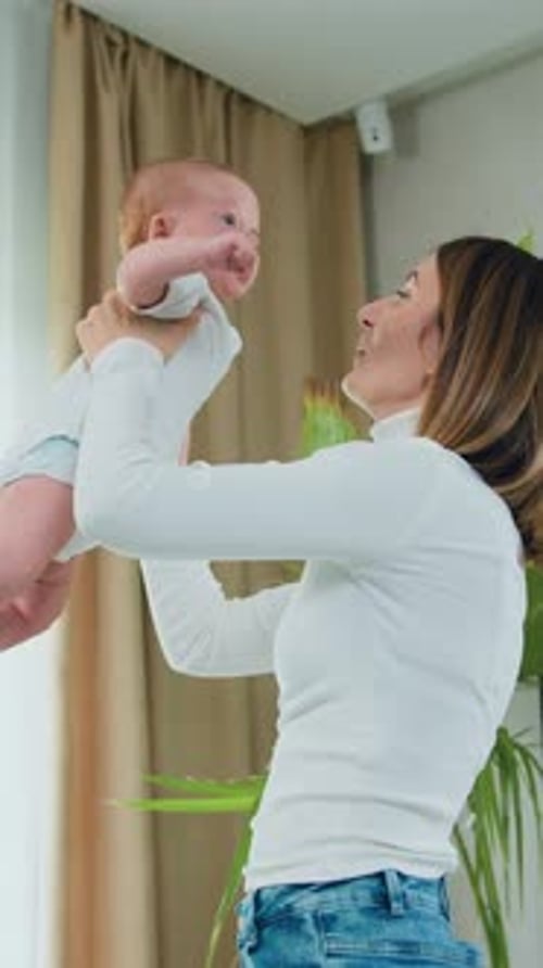 Loving Mother Holds and Kisses Her Baby