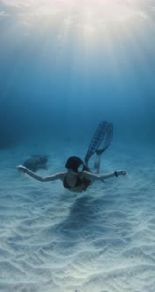 Freediver Woman Posing with Sand Underwater Freediving in Blue Ocean Over Sandy Sea Bottom with