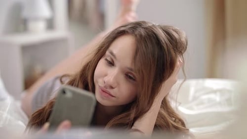 Smiling Woman Lying Down Taking Selfie on Bed
