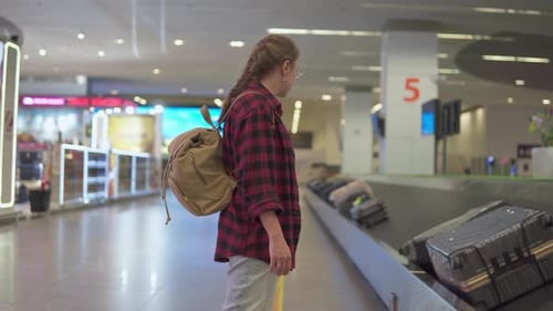 Female tourist with backpack is waiting her luggage in airport