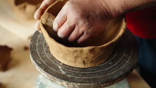 Close-Up of Hands Shaping Clay Bowl on Pottery Wheel in Sunlit Studio