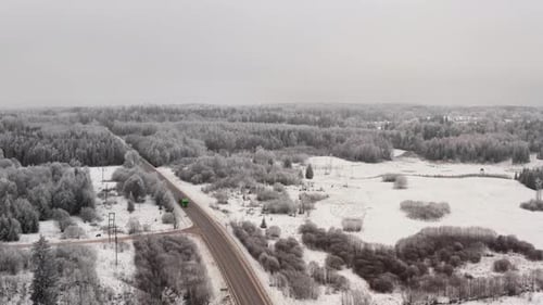 Aerial view of a two lane highway in countryside with truck passing by on a cloudy winter day. Frost