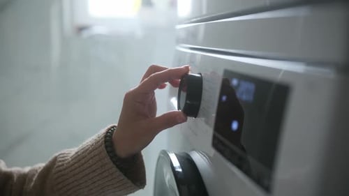 Woman Starting Modern Washing Machine Choosing Wash Cycle